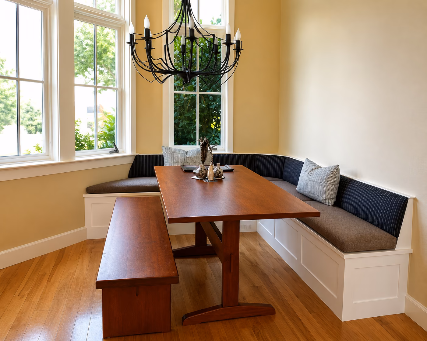 A custom corner dining banquette with tailored cushions in a window nook