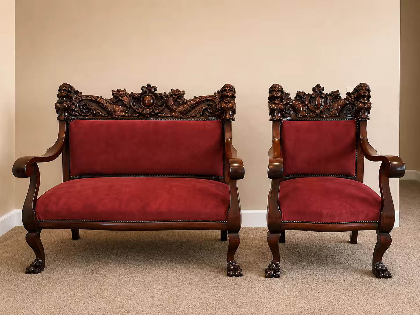 An antique carved lion-head settee and armchair reupholstered in red velvet